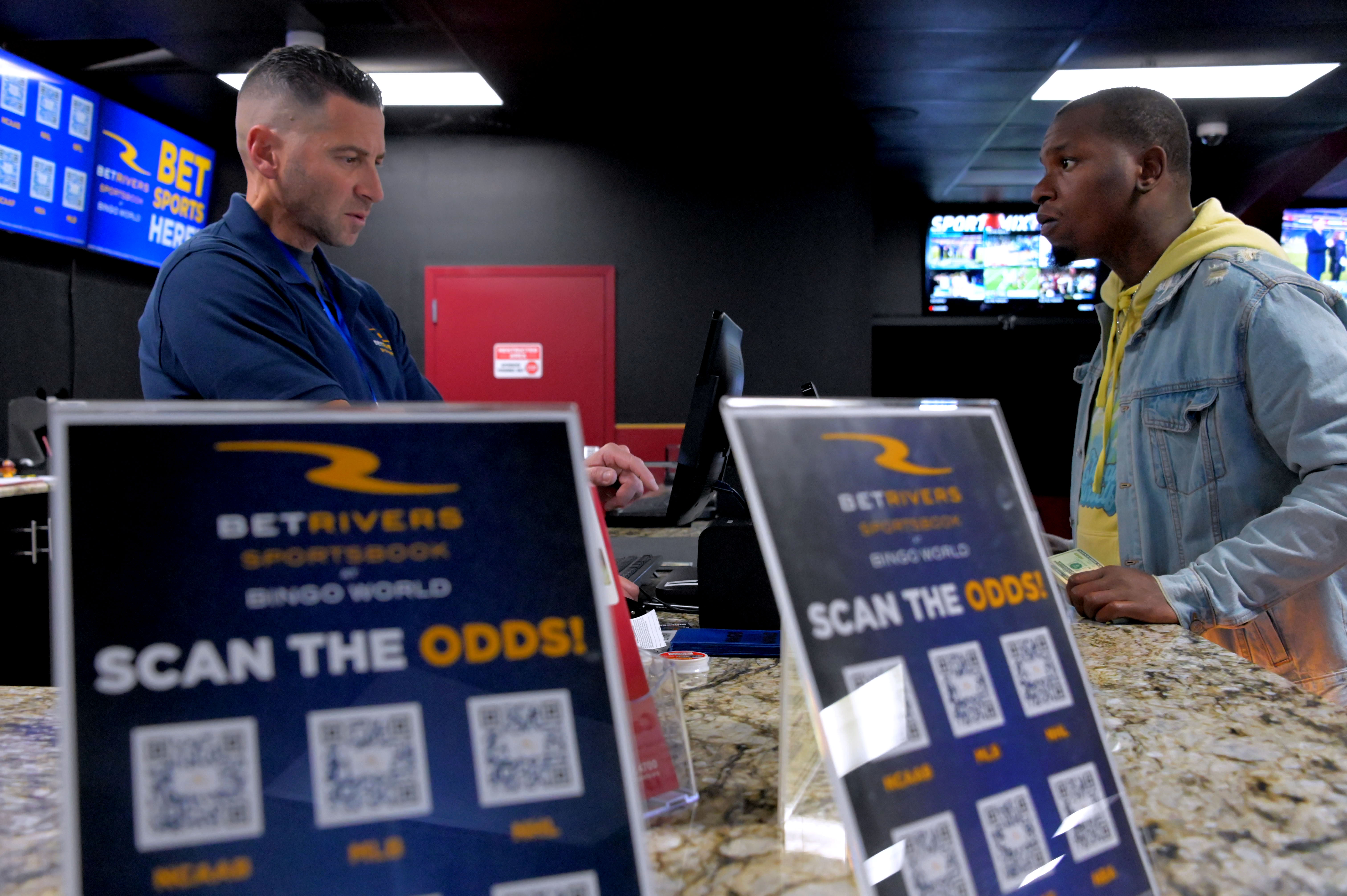 Marquise Culp of Baltimore, right, places bets on Monday on games with Jeff Silverman, who works behind the counter at BetRivers Sportsbook at Bingo World.